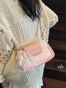 Pink checkered crossbody bag with pearl bow accessory shown on shoulder