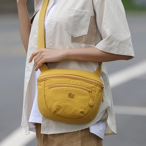 Detail shot of yellow nylon crossbody bag with dual zipper compartments and adjustable strap