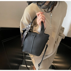 Detail of black pebble leather bucket bag with houndstooth silk scarf and shoulder strap