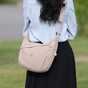 Detail of beige half-moon nylon crossbody bag with adjustable wide strap on model
