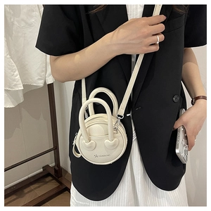 Close-up of beige circular mini bag with litchi grain texture and star logo detail