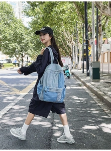 Detailed street style shot of a casual patchwork denim backpack worn by a model walking outdoors