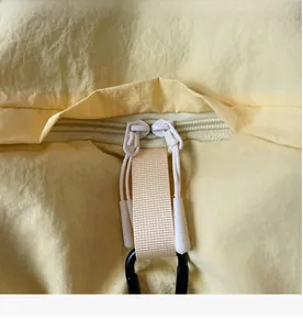 Detail view of smooth dual zippers and a black carabiner on a yellow functional backpack