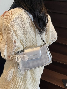 Metallic silver underarm bag with plaid pattern and pearl bow charm shown on model