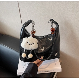 Détail du sac à bandoulière noir en demi-lune avec papillon argenté et pendentif nuage
