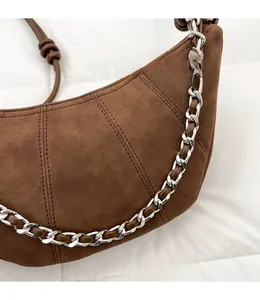 Detail of brown suede croissant bag with silver metal chain and segmented stitching