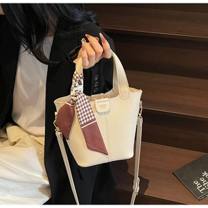 Detail of off-white lychee grain bucket bag with elegant silk scarf wrapped on handle