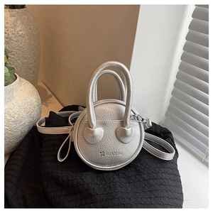 Close-up of a silver mini round crossbody bag with lychee texture and star pattern