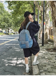 Detailed view of the patchwork denim backpack with blue panel stitching and outdoor lighting
