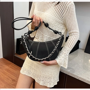 Detail of black crescent bag with contrast stitching and silver metal chain strap