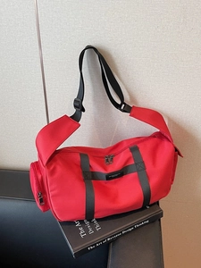 Grande borsa sportiva a cilindro in tela rossa con tracolla nera su divano in pelle