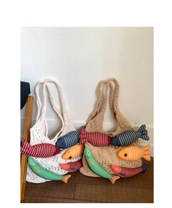 Detail of hand-knitted tote bags in cream and khaki featuring colorful plush fish charms