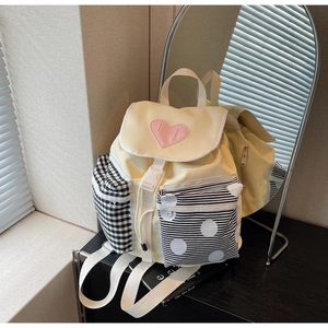 Detail view of yellow nylon backpack featuring pink heart patch and contrast patterned side pockets