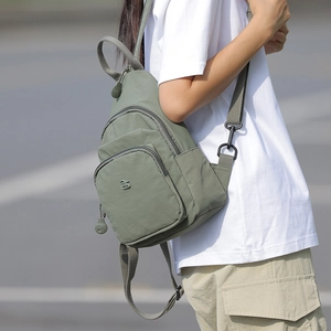 Close-up of a bean green nylon crossbody bag showing detailed zipper pockets and texture