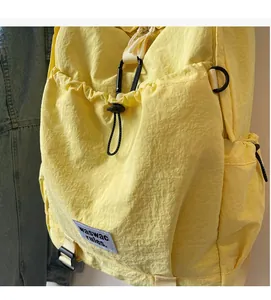 Detail of yellow nylon backpack featuring waterproof fabric and black D-ring hardware