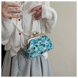 Detail of blue knitted kiss-lock bag featuring 3D bear floral accents and pearl handle