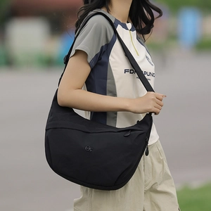 Detail of black nylon dumpling crossbody bag featuring spacious interior and round logo