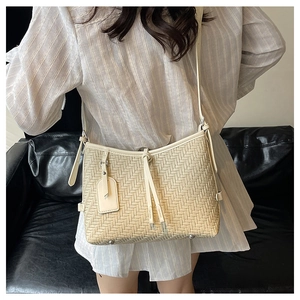 Elegant beige woven shoulder bag featuring a drawstring design and a minimalist chic look