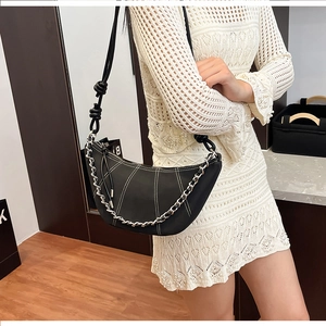 Detail of black crescent shoulder bag featuring white contrast stitching and silver chain