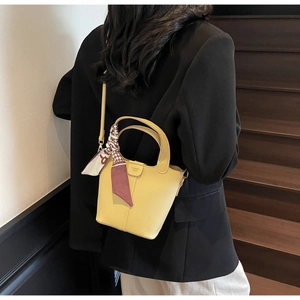 Detail of yellow lychee textured bucket bag with decorative silk scarf and fashion logo