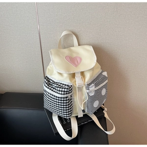 Detail of cream canvas backpack featuring pink heart patch and black pattern side pockets