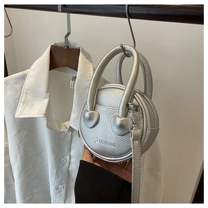 Detail of silver round mini crossbody bag with heart-shaped hardware and litchi texture
