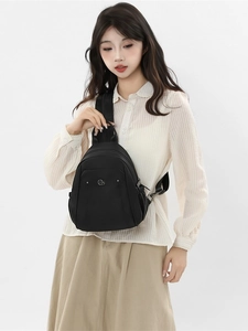 Minimalist black nylon backpack for women with metal logo detail and front zipper pocket