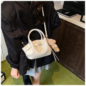 Detailed texture of white crocodile pattern bucket bag with a cute brown bear charm