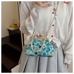 Detail view of sky blue shell bag with floral bear print and pearl chain strap