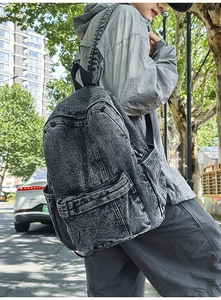 Detail of dark grey washed denim backpack featuring wide straps and retro texture