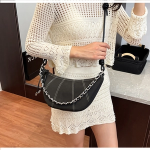 Detail view of black crescent bag with white contrast stitching and chain strap