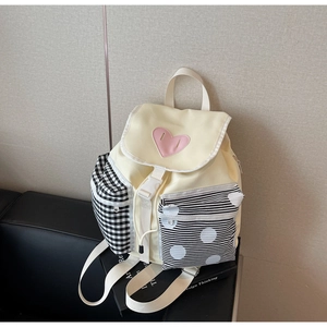 Detail view of canvas backpack featuring pink heart patch and contrast patterned pockets