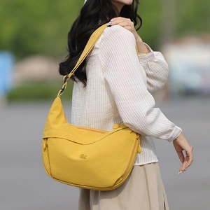 Detail view of yellow nylon half-moon crossbody bag with side zipper pocket and logo