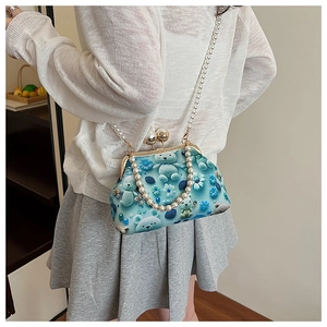 Detail of teal kiss-lock bag featuring plush bear print and elegant double pearl chains