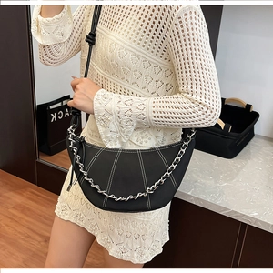 Detail of a black crescent shoulder bag with contrast white stitching and chain strap