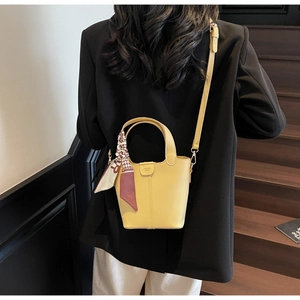 Detail of yellow lychee leather bucket bag with printed silk scarf and fashion text