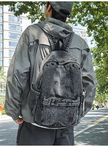 Detailed view of deep grey washed denim backpack with vintage texture and large front pocket