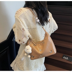 Détail du sac hobo camel avec clous papillon et bandoulière ornée de perles blanches