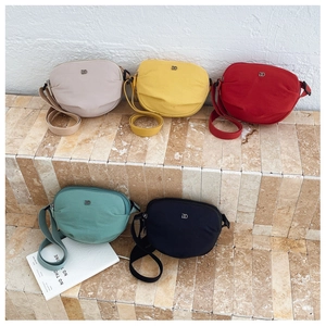 Collection of half-moon nylon crossbody bags in beige, yellow, red, teal, and black