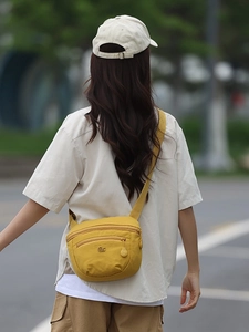 Vibrant yellow nylon crescent crossbody bag with multi-pocket design and wide fabric strap