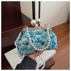 Detailed view of blue shell bag with pearl chain strap and teddy bear crochet pattern