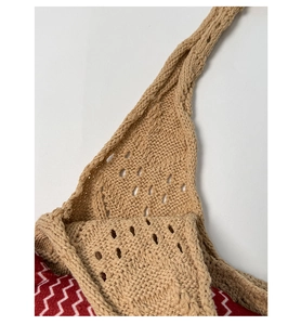 Detailed macro view of khaki hollow crochet knit pattern with braided shoulder strap