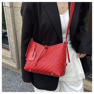 Detail of red woven texture shoulder bag featuring adjustable strap and silver metal feet
