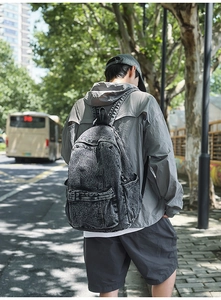 Outdoor shot of a washed denim backpack in charcoal grey with multiple pocket details