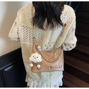 Détail du sac à bandoulière kaki clair avec breloque papillon et pendentif nuage doux