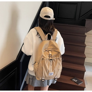 Modern beige nylon backpack for women featuring large drawstring pocket and adjustable straps