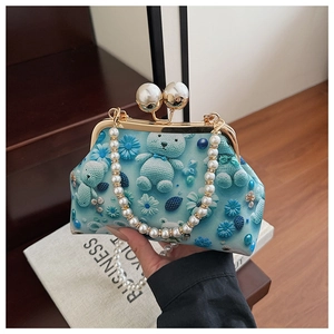 Detail of light blue shell bag with bear pattern, pearl clasp, and chain handle
