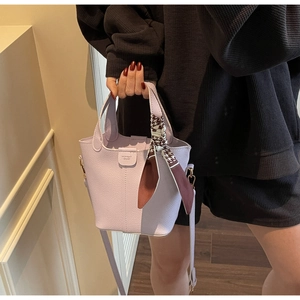 Detail view of lavender leather bucket bag with a silk scarf tied on handle