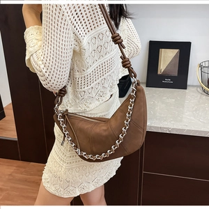 Macro detail of brown crescent shoulder bag with silver chain and knot strap texture