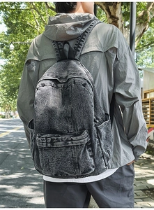 Outdoor back view of a vintage washed denim backpack in dark grey with adjustable straps